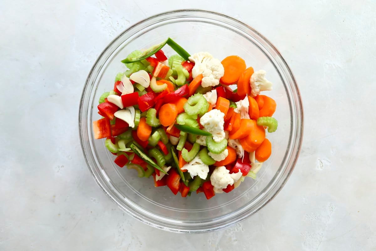 A clear mixing bowl with vegetables for Giardiniera.