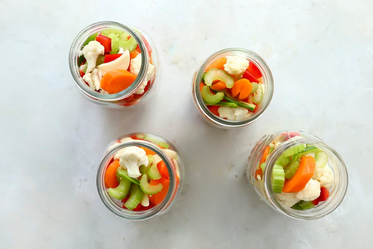 Four mason jars with vegetables.