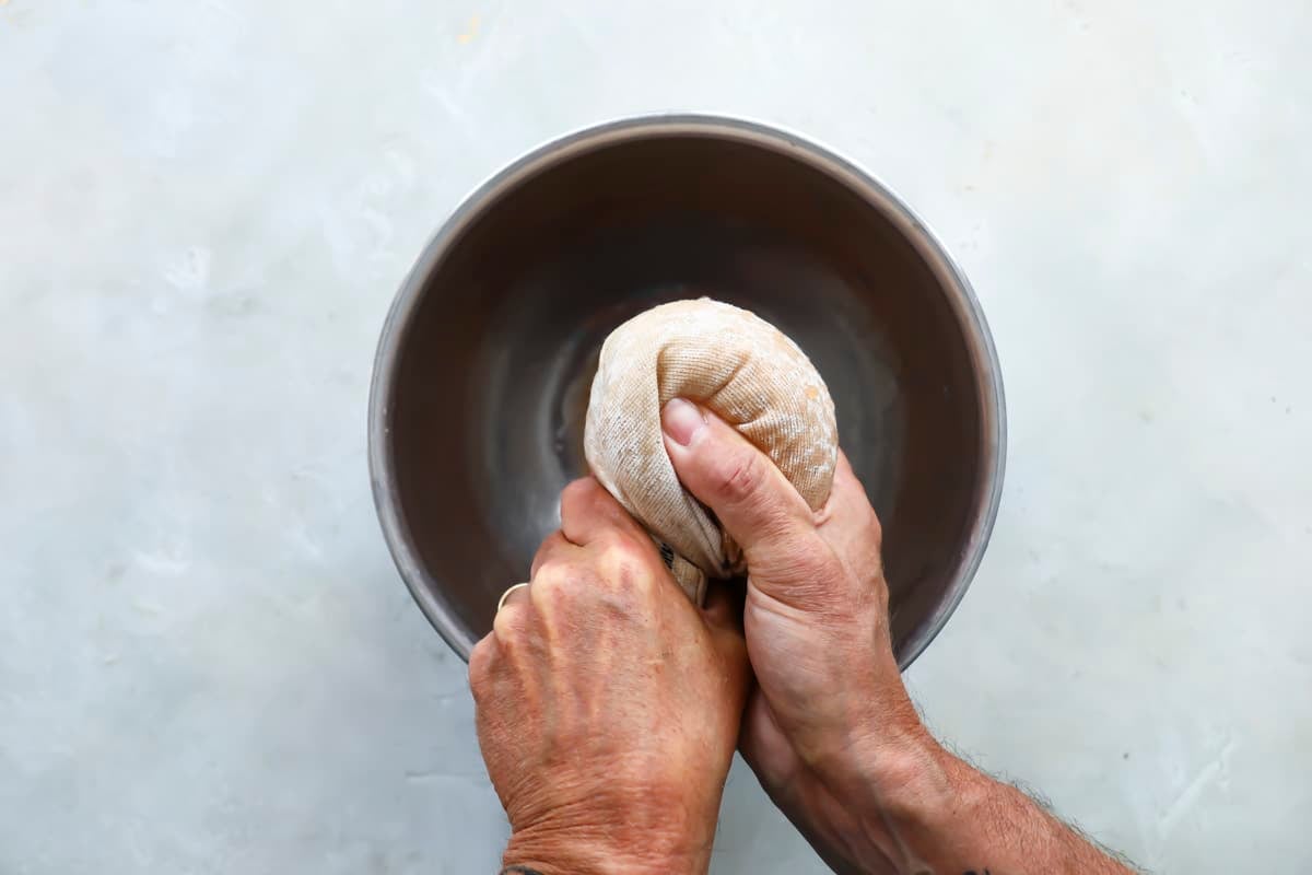 Someone squeezing liquid out of shredded potatoes.