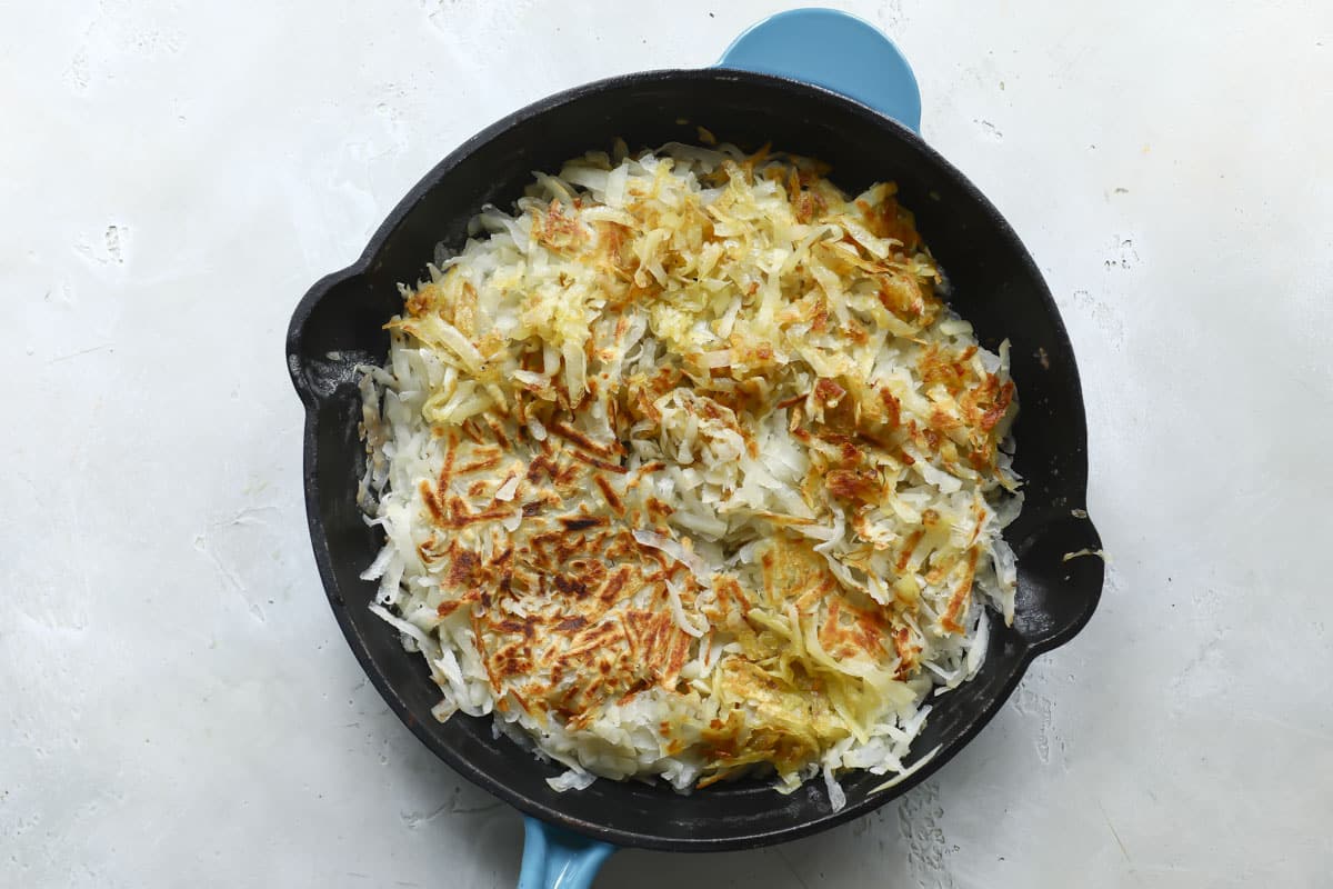 Hash browns cooking in a skillet.
