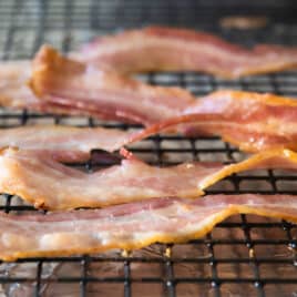 Cooked bacon on a rack set over a foil-lined baking sheet.