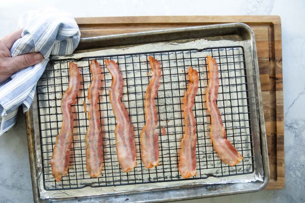 Cooked bacon on a rack set over a foil-lined baking sheet.
