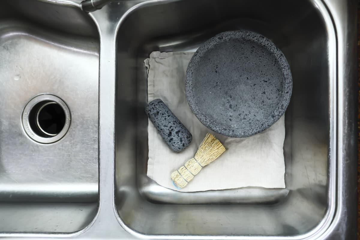 A molcajete and root brush in a sink.