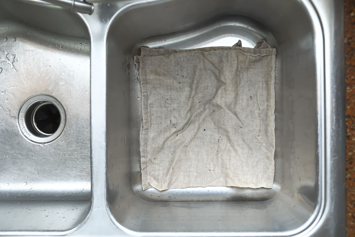 A sink with a towel showing debris that has fallen out of a molcajete.