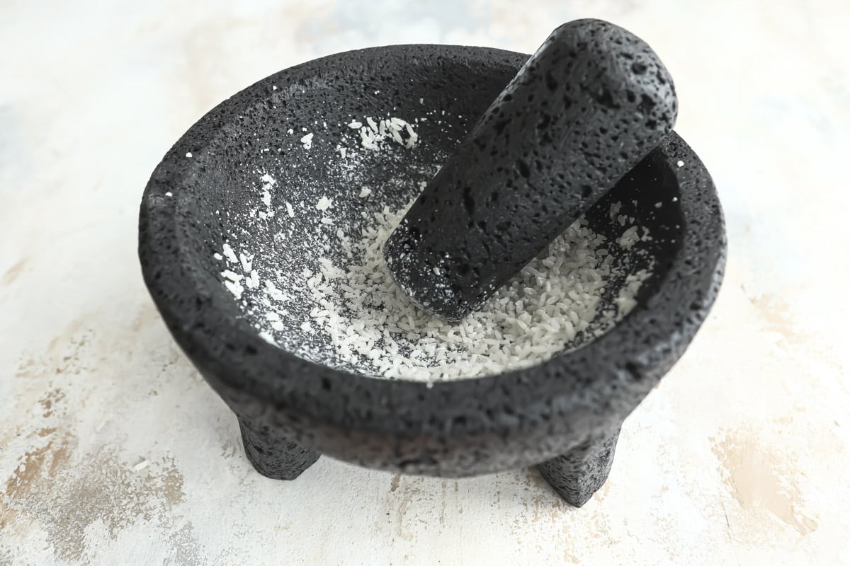 Grinding rice in a molcajete to clean it.