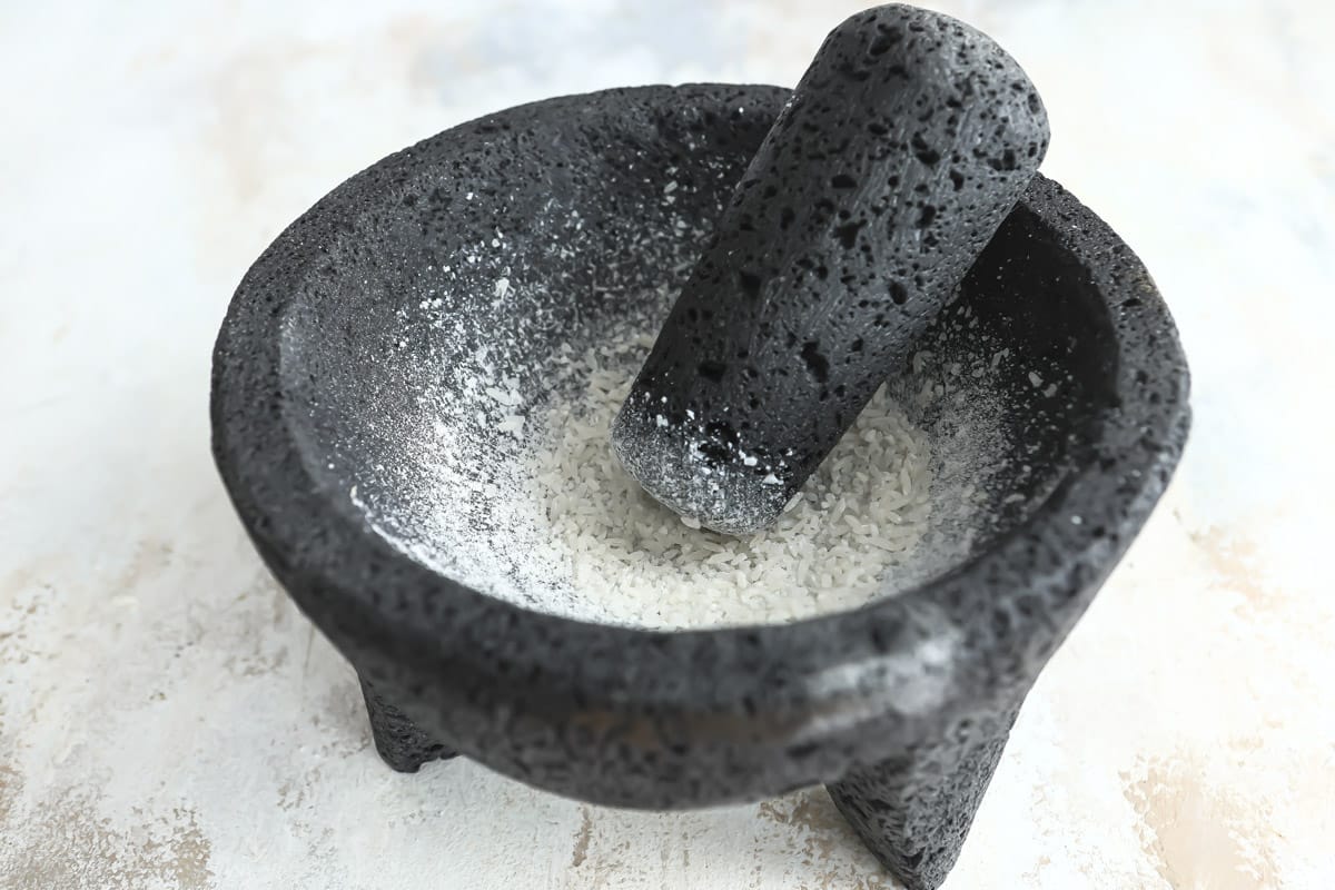 Grinding rice in a molcajete to clean it.