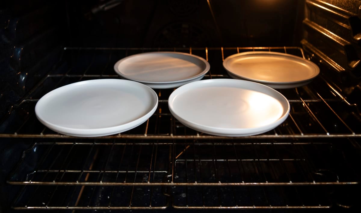 Four plates warming in an oven.