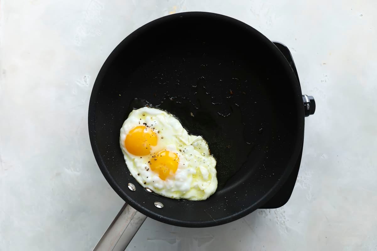Two eggs frying in a skillet.