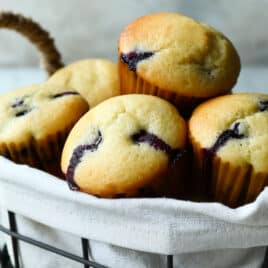 Lemon blueberry muffins in a basket with a bowl of blueberries.