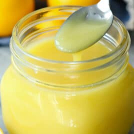Lemon curd in a clear glass jar.