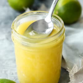 A jar of lime curd with a spoon scooping some out.