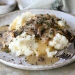 A plate with mashed potatoes and mushroom gravy.