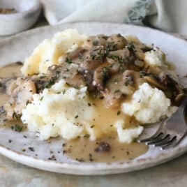 A plate with mashed potatoes and mushroom gravy.