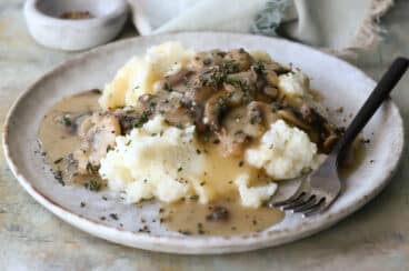 A plate with mashed potatoes and mushroom gravy.