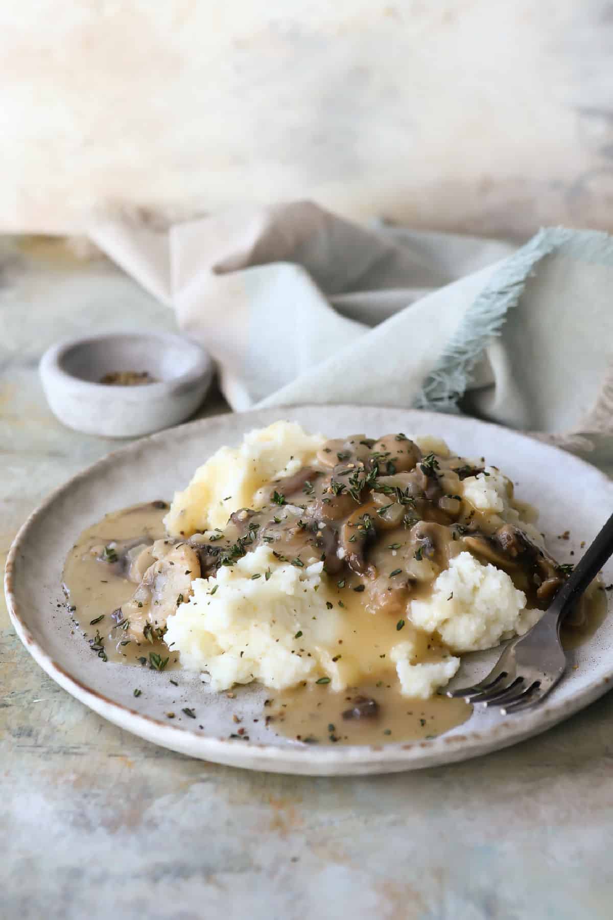 A plate with mashed potatoes and mushroom gravy.