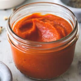 A small clear jar of Romesco sauce.