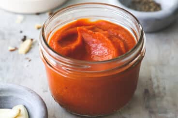 A small clear jar of Romesco sauce.