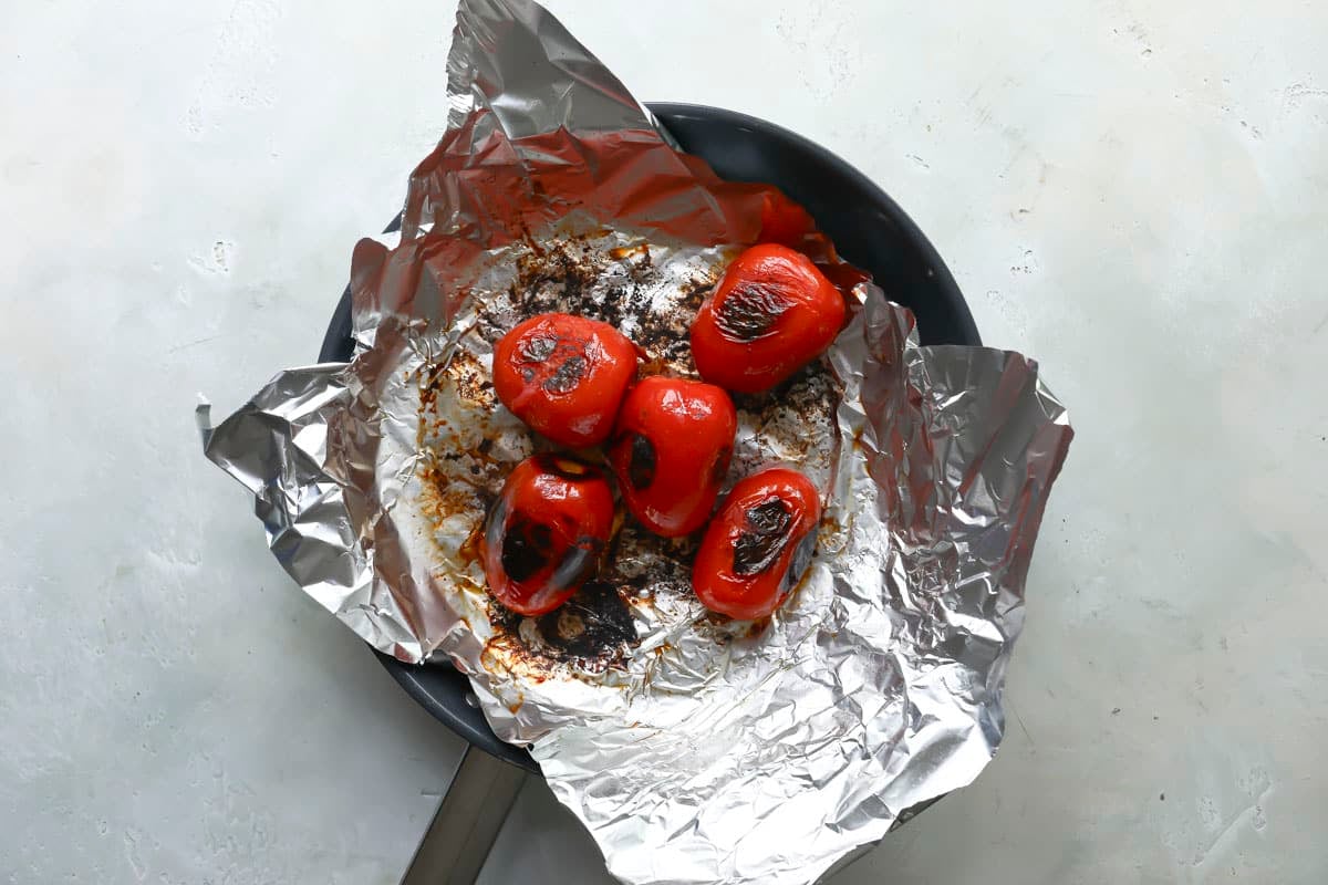 Roasted tomatoes on aluminum foil in a skillet.