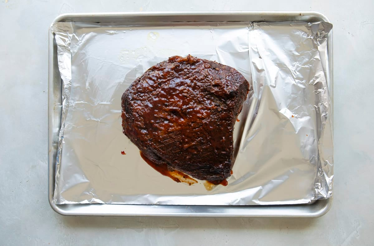 A bbq beef brisket on an aluminum foil lined baking sheet.