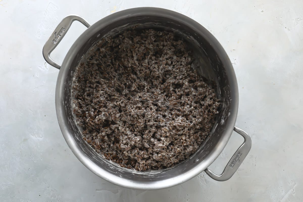 Cocoa krispies stirred into melted butter and marshmallows in a pan.