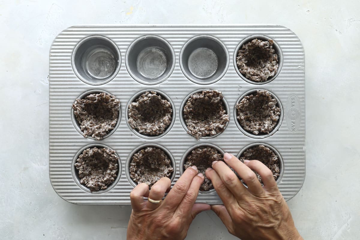 Pressing cocoa krispies into a muffin pan for nests.