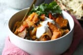 A bowl of eggplant curry with yogurt on top.