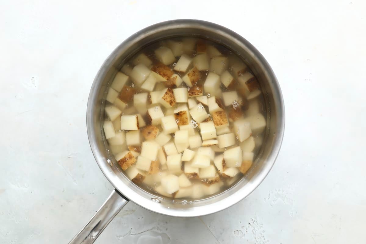 Boiling cut potatoes in water in a saucepan.