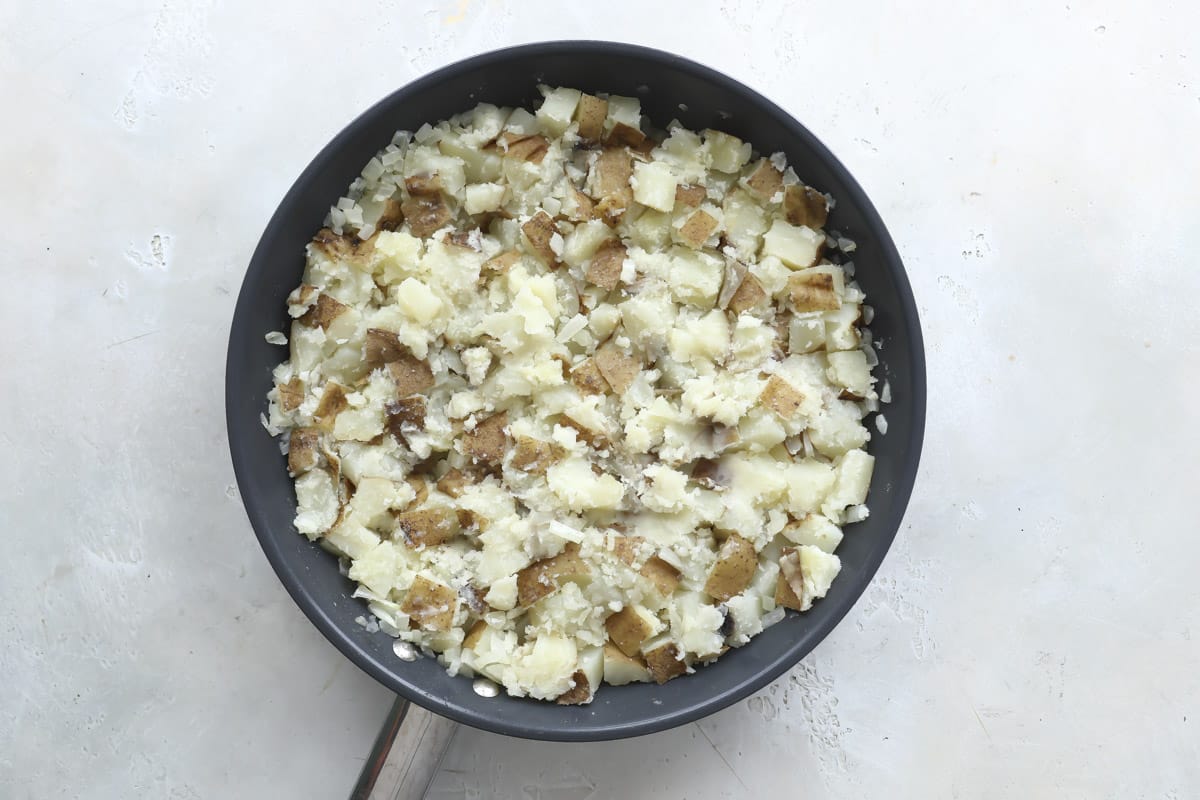 Cooking potatoes and onions in a skillet.