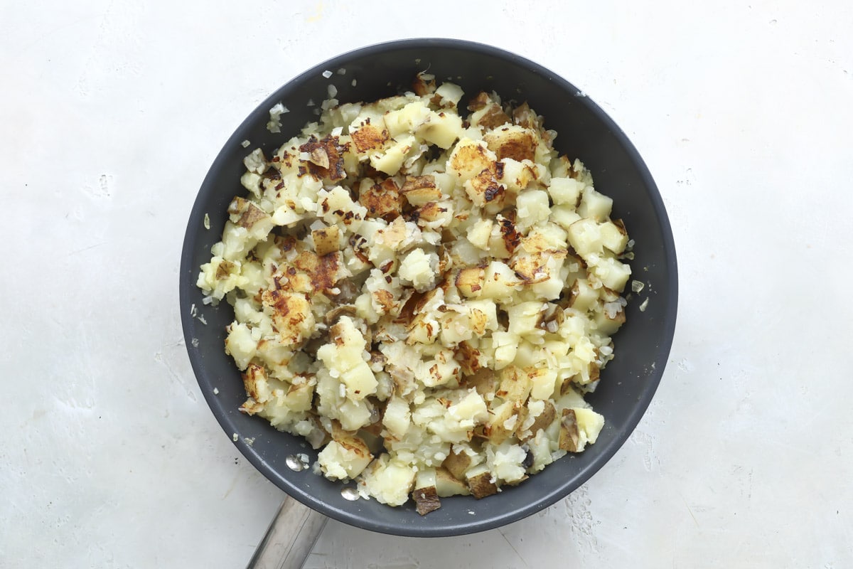 Cooking potatoes and onions in a skillet.