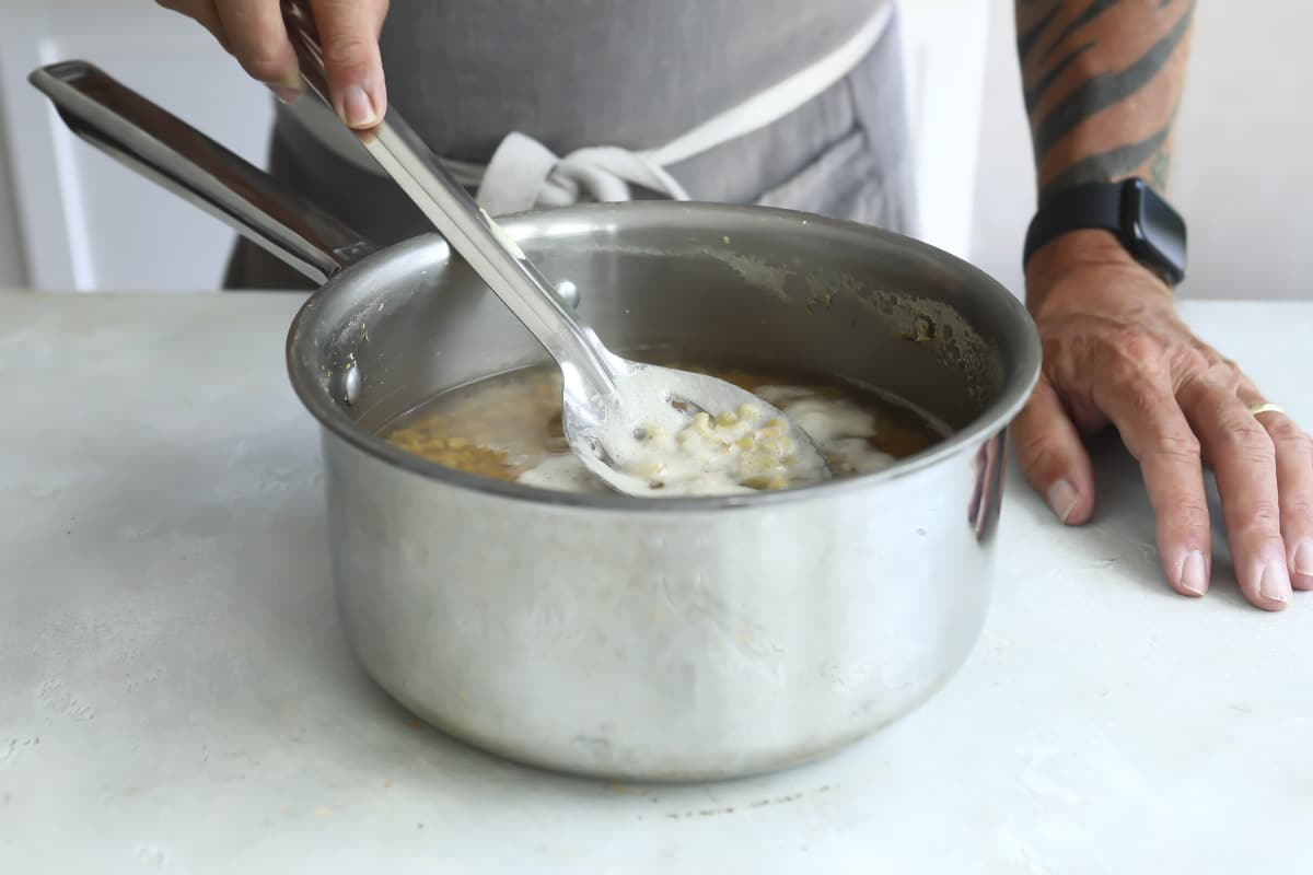 Skimming foam off a pot of red lentils.