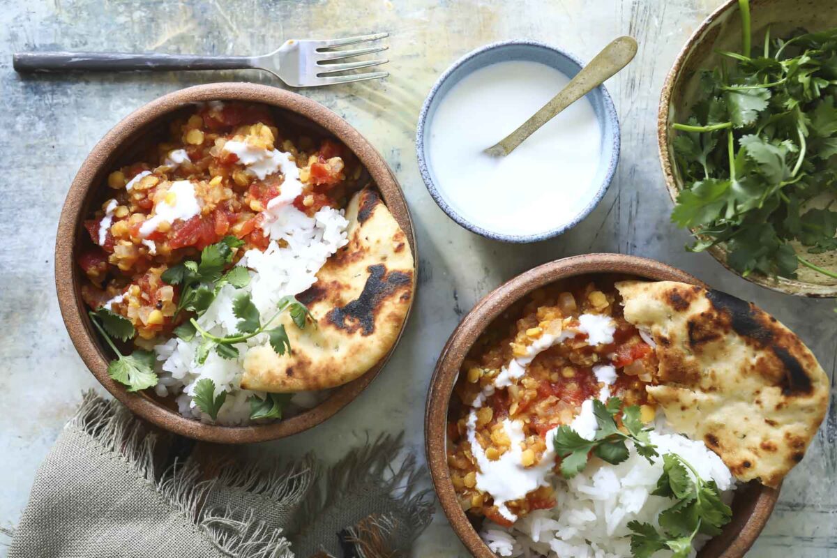 A plate of masoor dal with rice, yogurt, and naan.