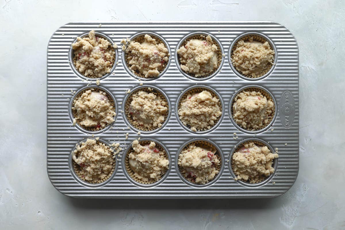 Raspeberry muffin batter in a muffin tin.