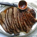 A serving platter with a slow cooker beef brisket slices.