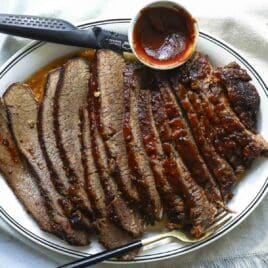 A serving platter with a slow cooker beef brisket slices.