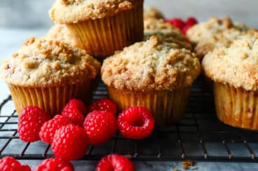 A cooling rack full of raspberry muffins.