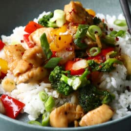 A bowl of chicken stir fry on top of white rice.