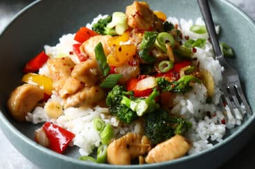 A bowl of chicken stir fry on top of white rice.