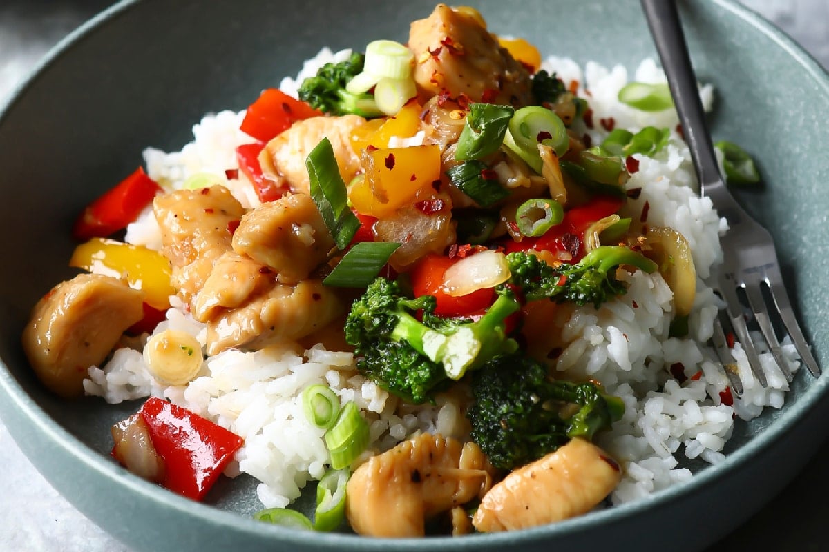 A bowl of chicken stir fry on top of white rice.
