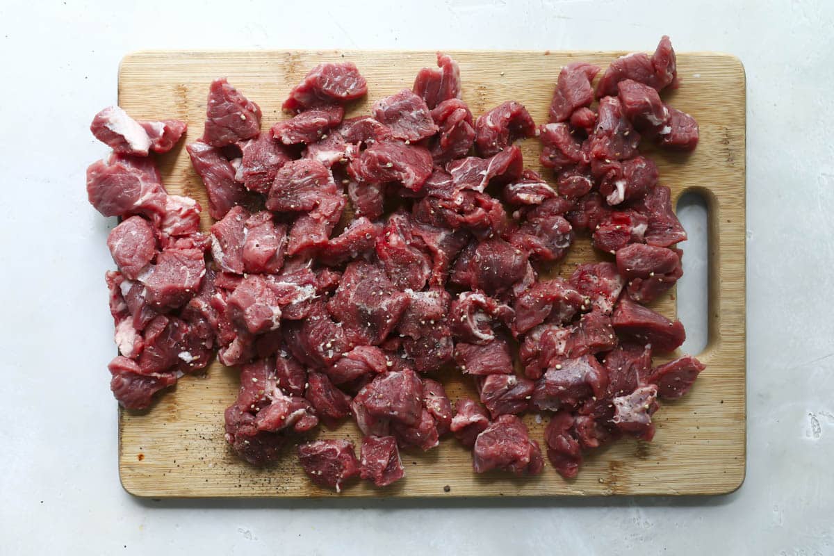 Beef roast cut up on a cutting board for borscht.