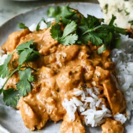 A plate of butter chicken over basmati rice.