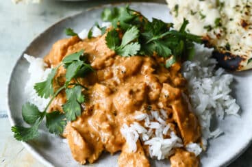 A plate of butter chicken over basmati rice.