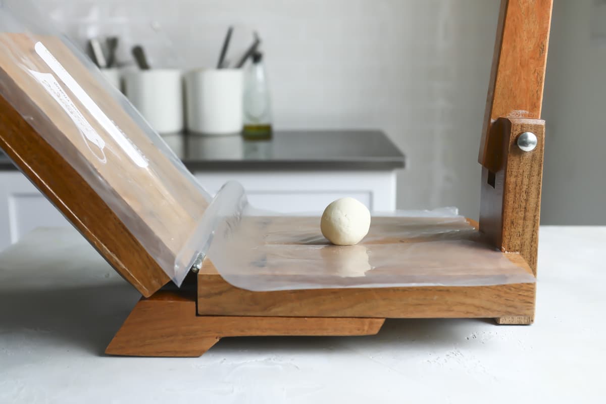 A bowl for corn tortillas on a press.