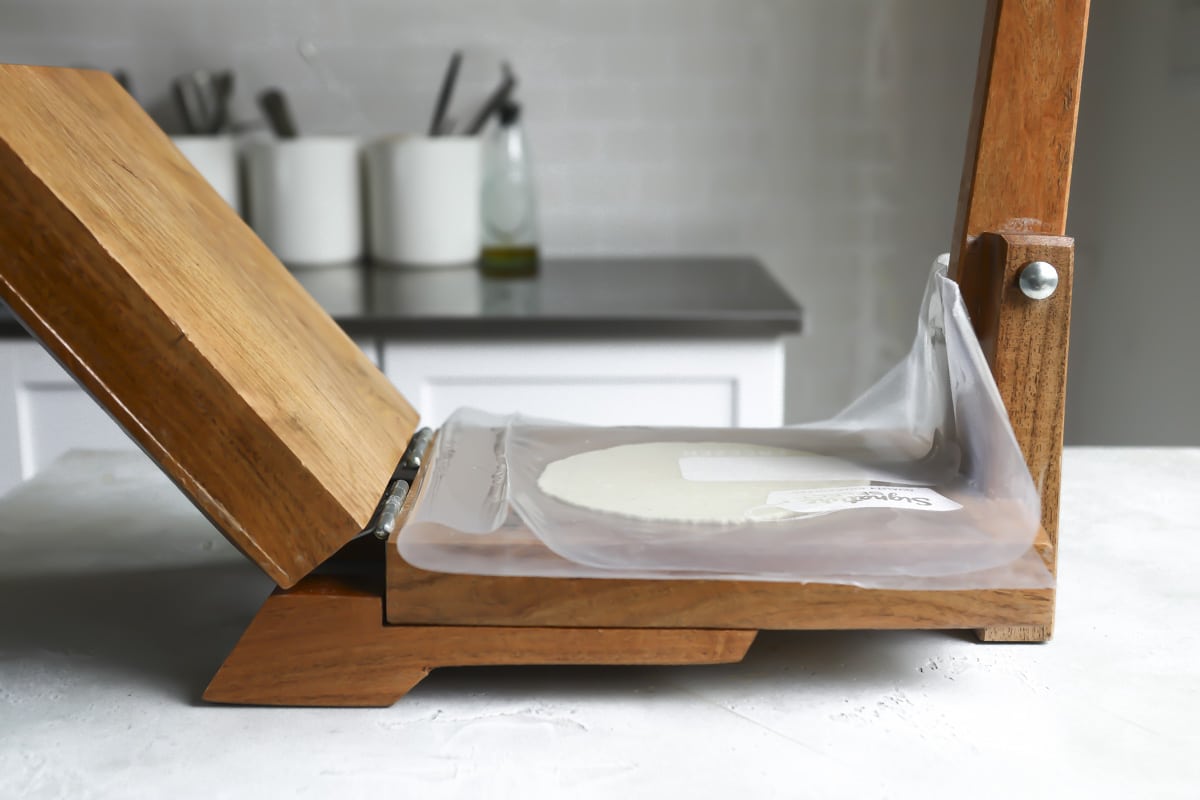 Pressing a corn tortilla on a tortilla press.
