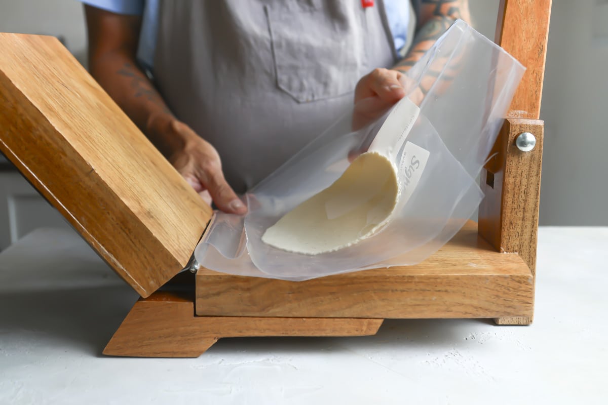 Pressing a corn tortilla on a tortilla press.