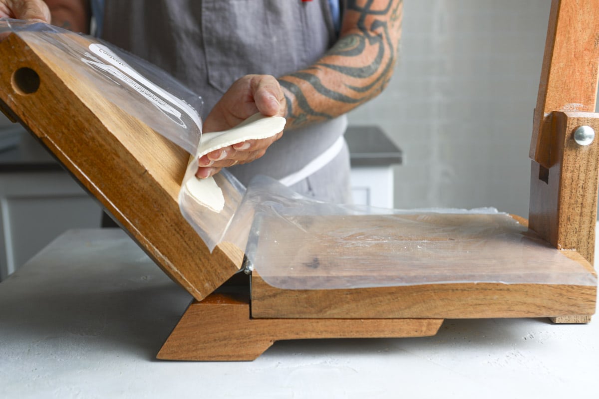 Pressing a corn tortilla on a tortilla press.