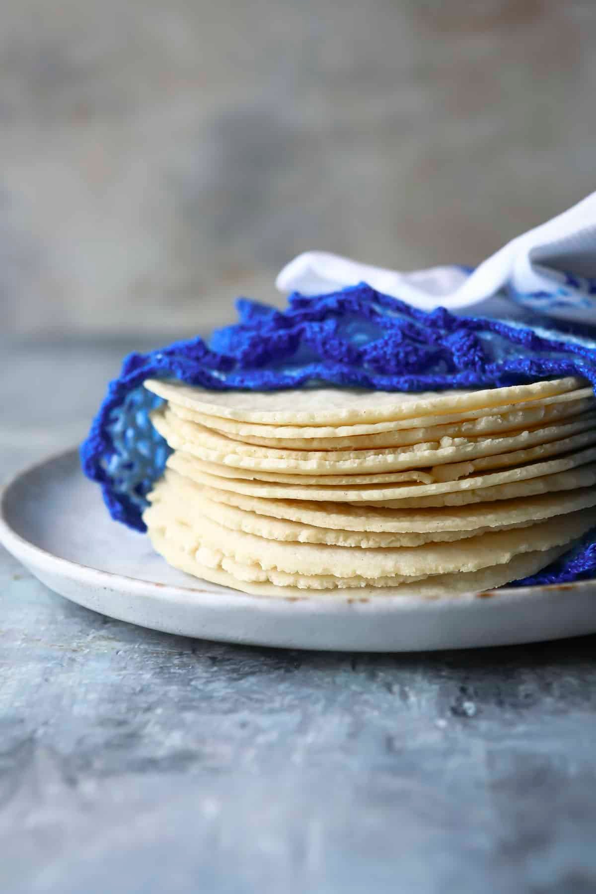 A stack of corn tortillas on a plate.