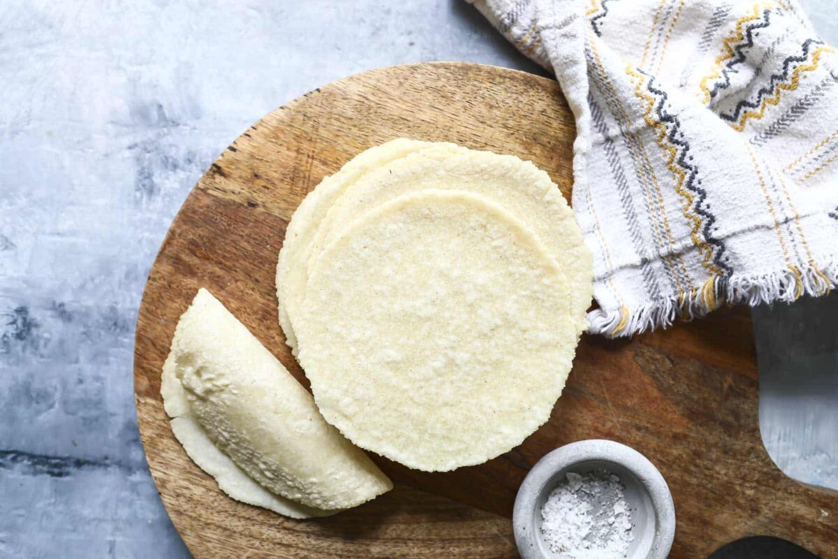 A stack of corn tortillas on a wooden platter.