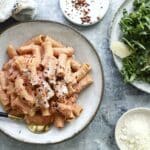Penne alla vodka on a gray plate next to a plate of arugula salad.