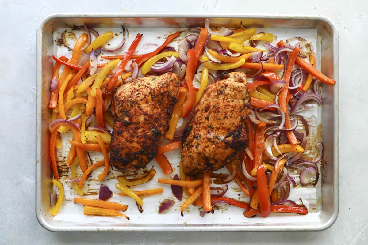 Sheet pan chicken fajitas on a baking sheet after cooking.
