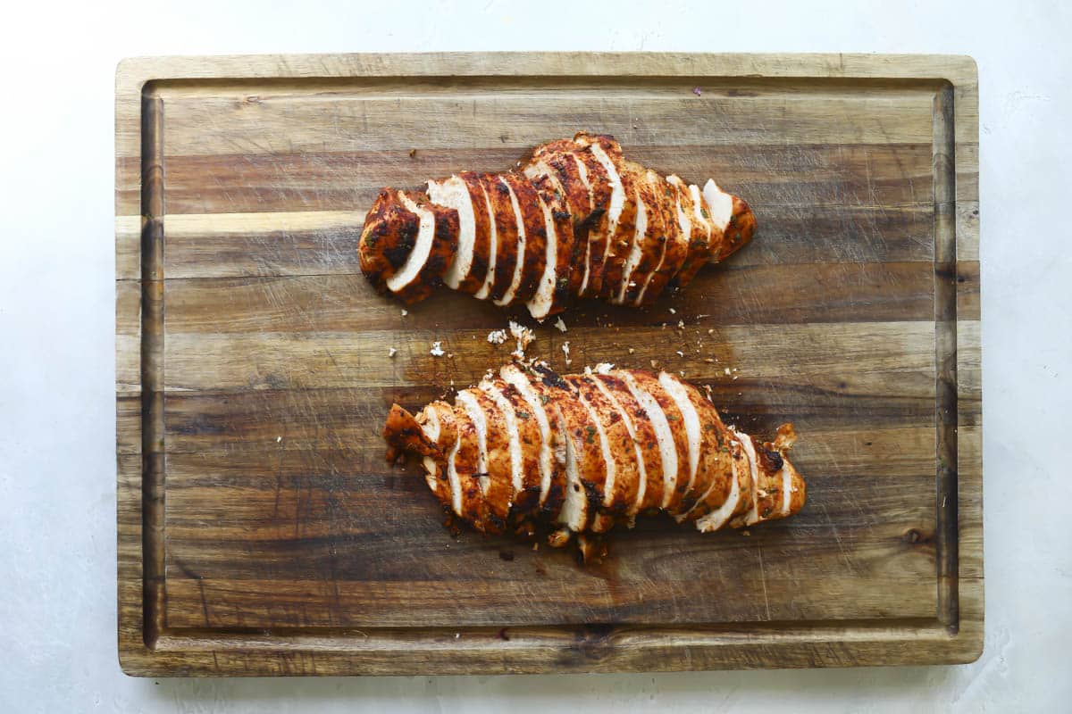 Sheet pan fajita chicken sliced on a cutting board.